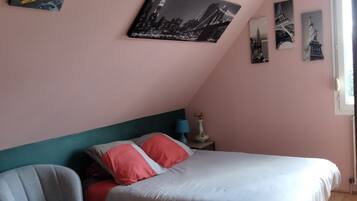 A bedroom with a bed, a chair, a nightstand, and wall art.