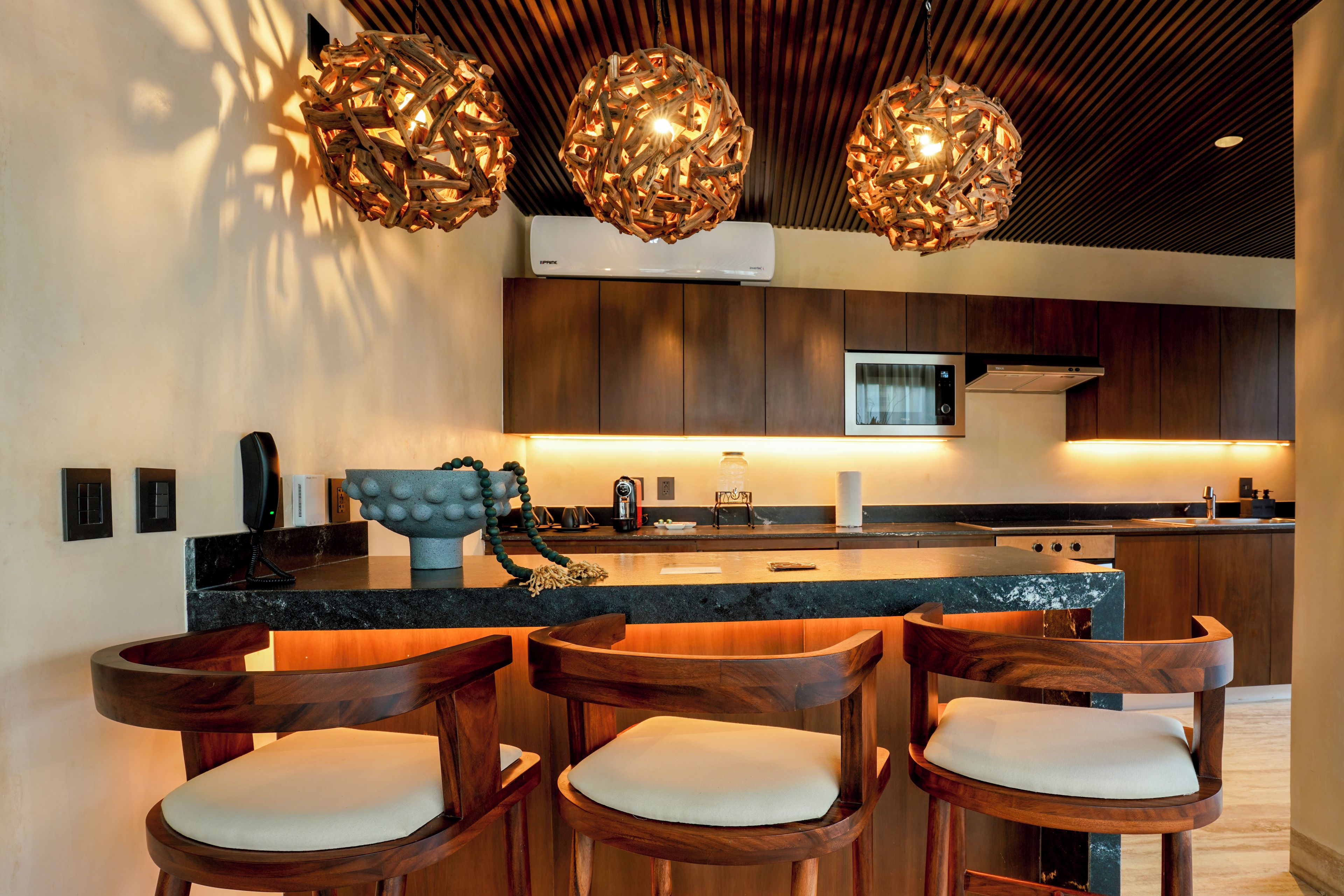 Une cuisine moderne avec des tabourets de bar en bois, des luminaires suspendus et un îlot central.