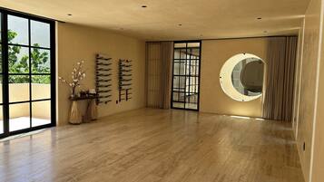 A spacious room with a large window, a wooden floor, a wall-mounted mirror, and a sliding door.