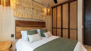 A bedroom with a wooden headboard, a bed with white and green bedding, a green throw blanket, a wooden nightstand, and a wall-mounted light fixture.