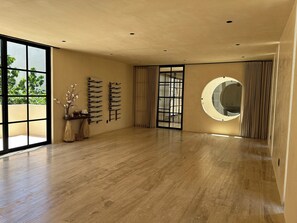 Una habitación amplia con un gran ventanal, suelo de madera, espejo fijado a la pared y puerta corredera.