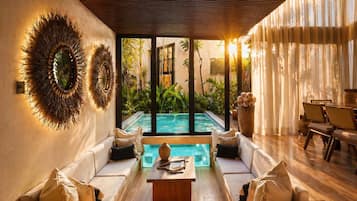 A modern indoor pool area with a sofa and chairs facing the pool, a wooden coffee table, and a view of the outdoor pool.