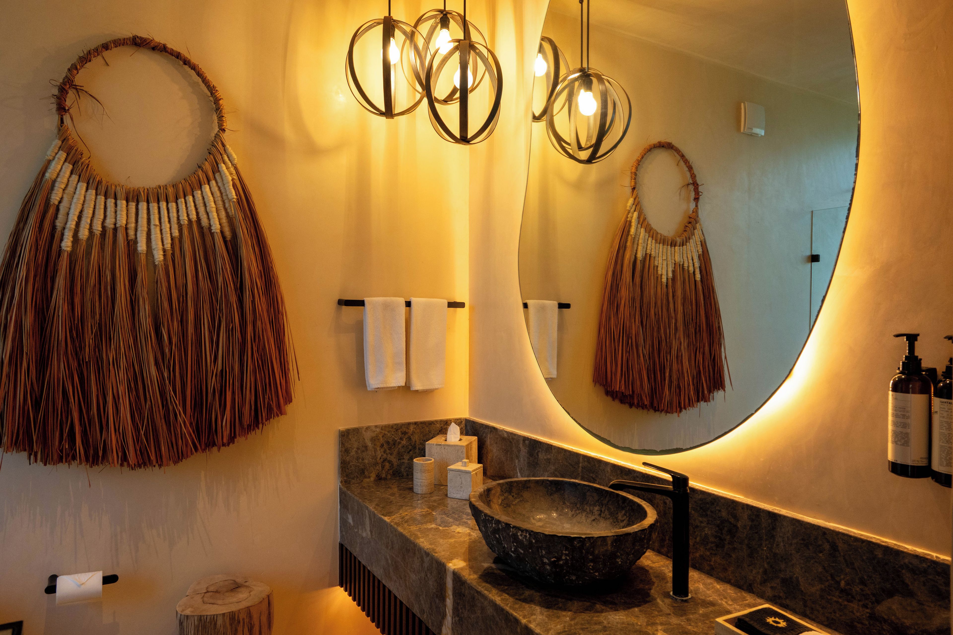 A bathroom with a large mirror, a stone sink, and a towel rack.
