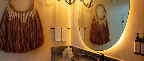A bathroom with a large mirror, a stone sink, and a towel rack.
