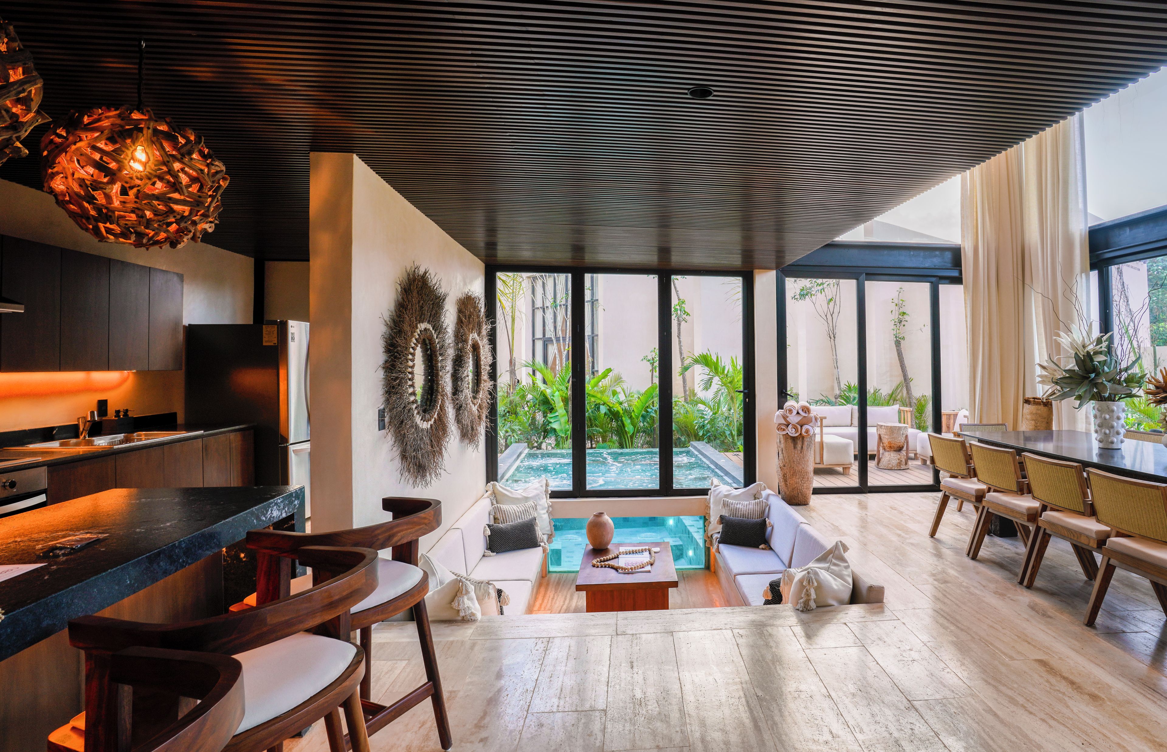 Une cuisine moderne dotée d’un bar, d’un coin salon avec vue sur une piscine et d’un espace repas avec vue sur l’extérieur.