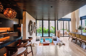 A modern kitchen with a bar area, a seating area with a view of a pool, and a dining area with a view of the outdoors. - Trobbu Boutique Collection Riviera Maya - All Inclusive (Tulum)