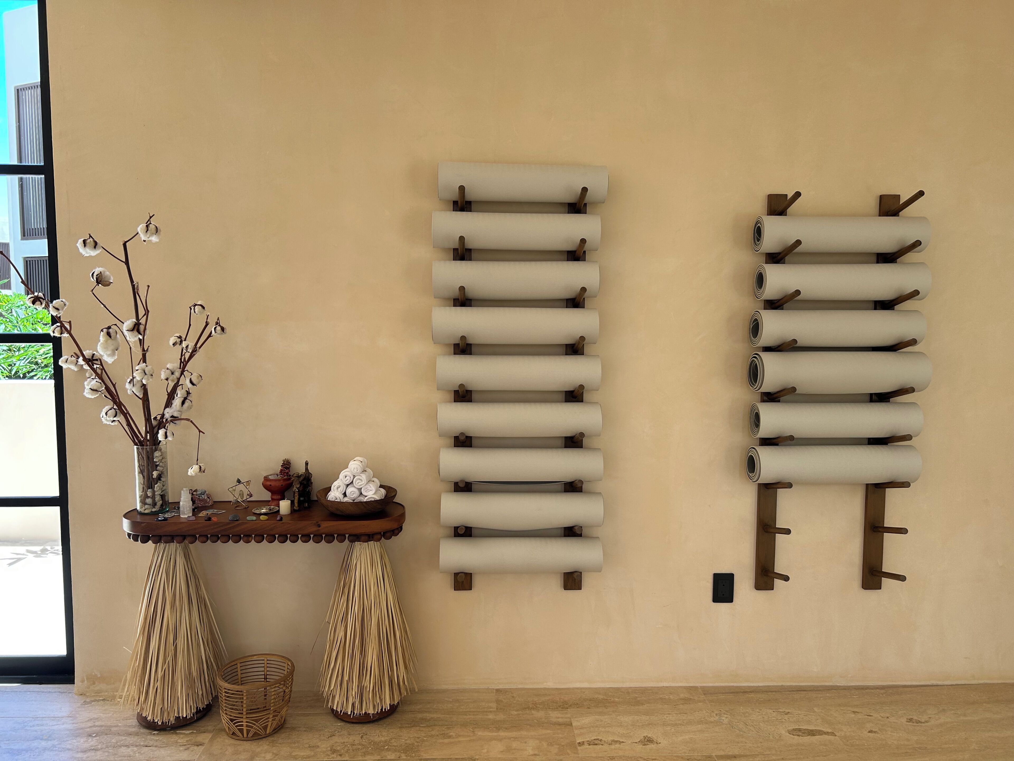 A room with a wooden table, a vase with dried branches, and two wall-mounted towel racks.