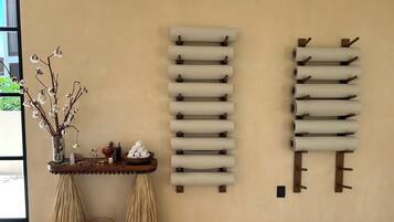A room with a wooden table, a vase with dried branches, and two wall-mounted towel racks.