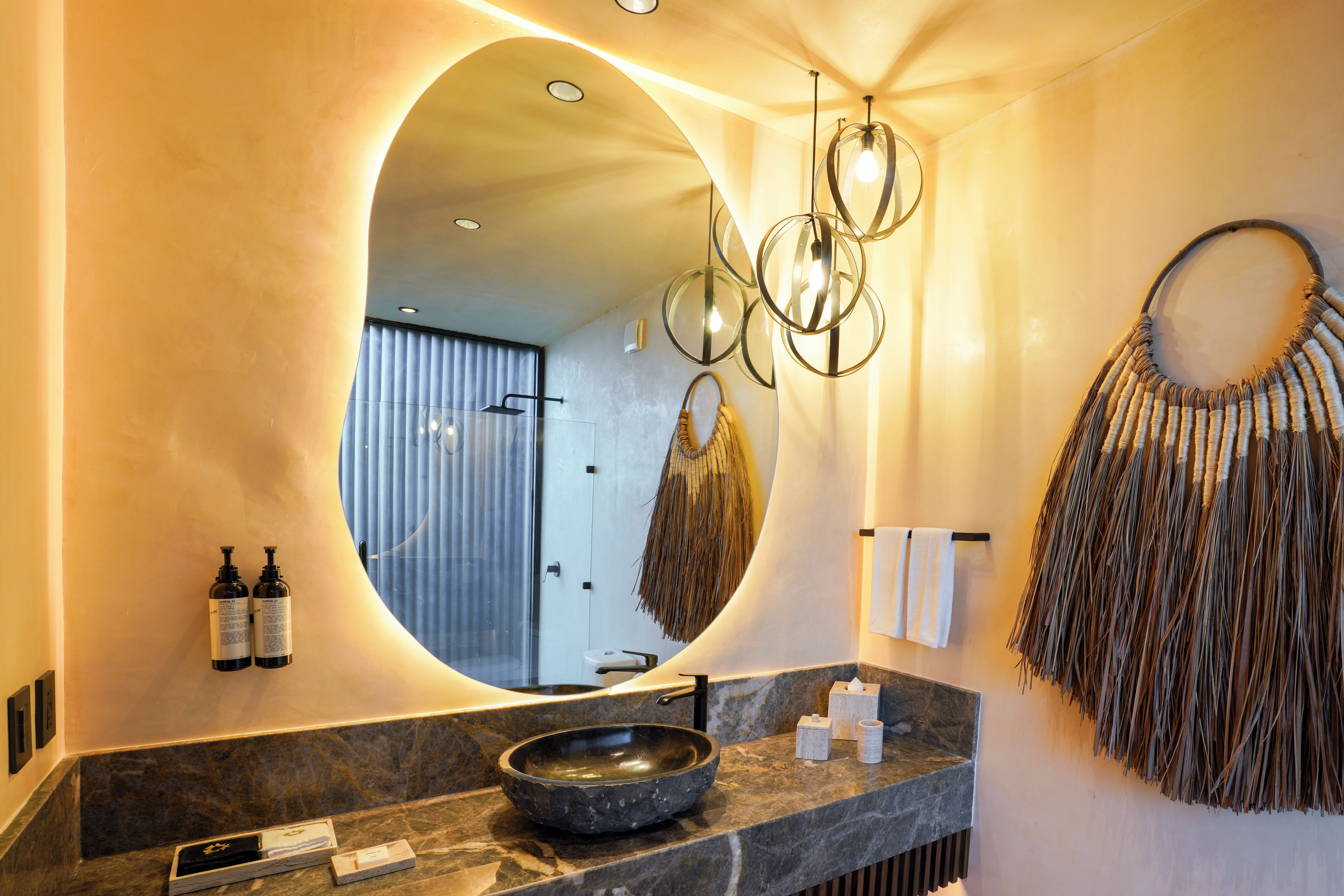 A bathroom with a round mirror, a bowl sink, and a decorative wall piece.