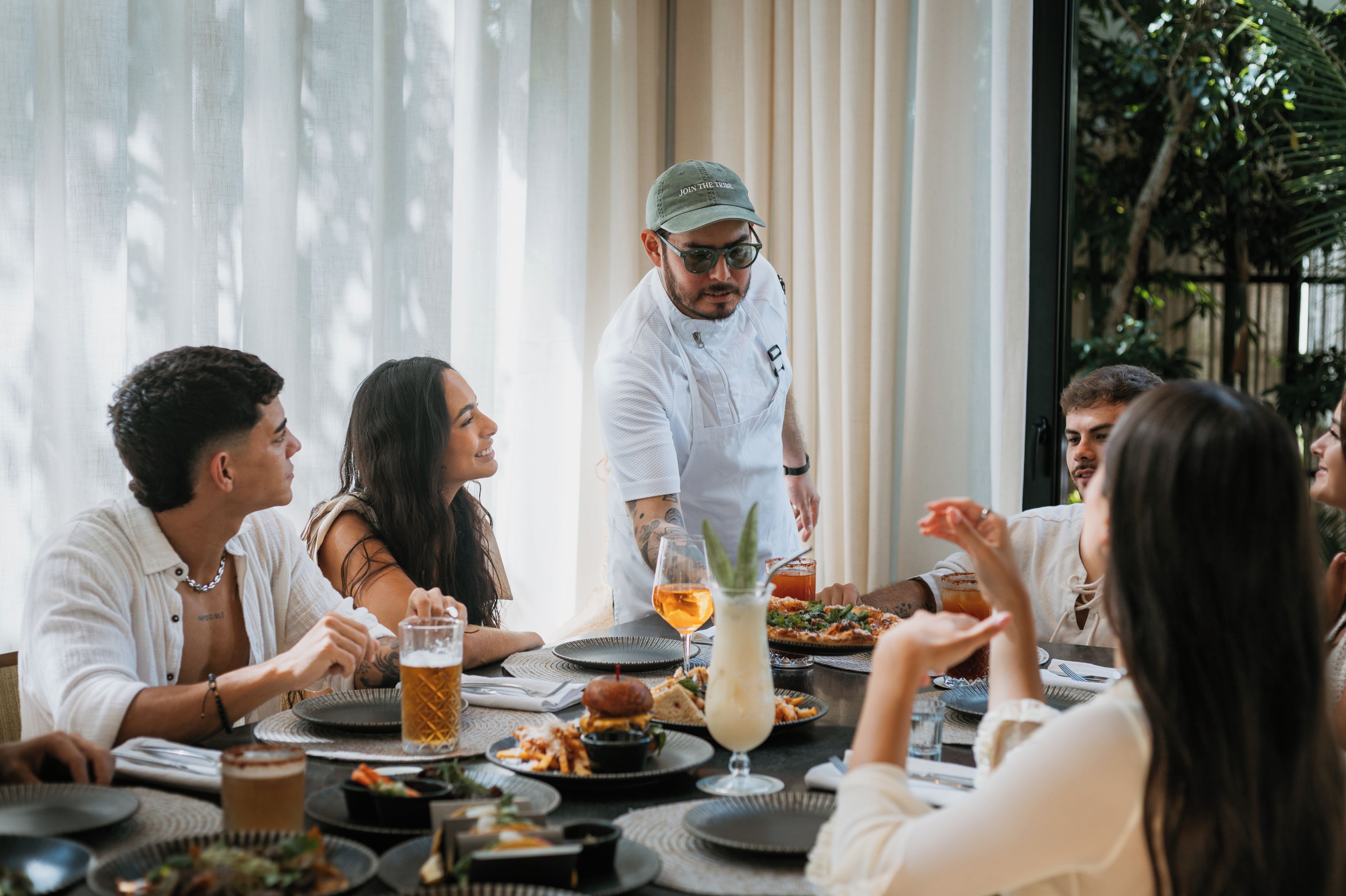 A group of people dining at a table with various dishes and drinks.
