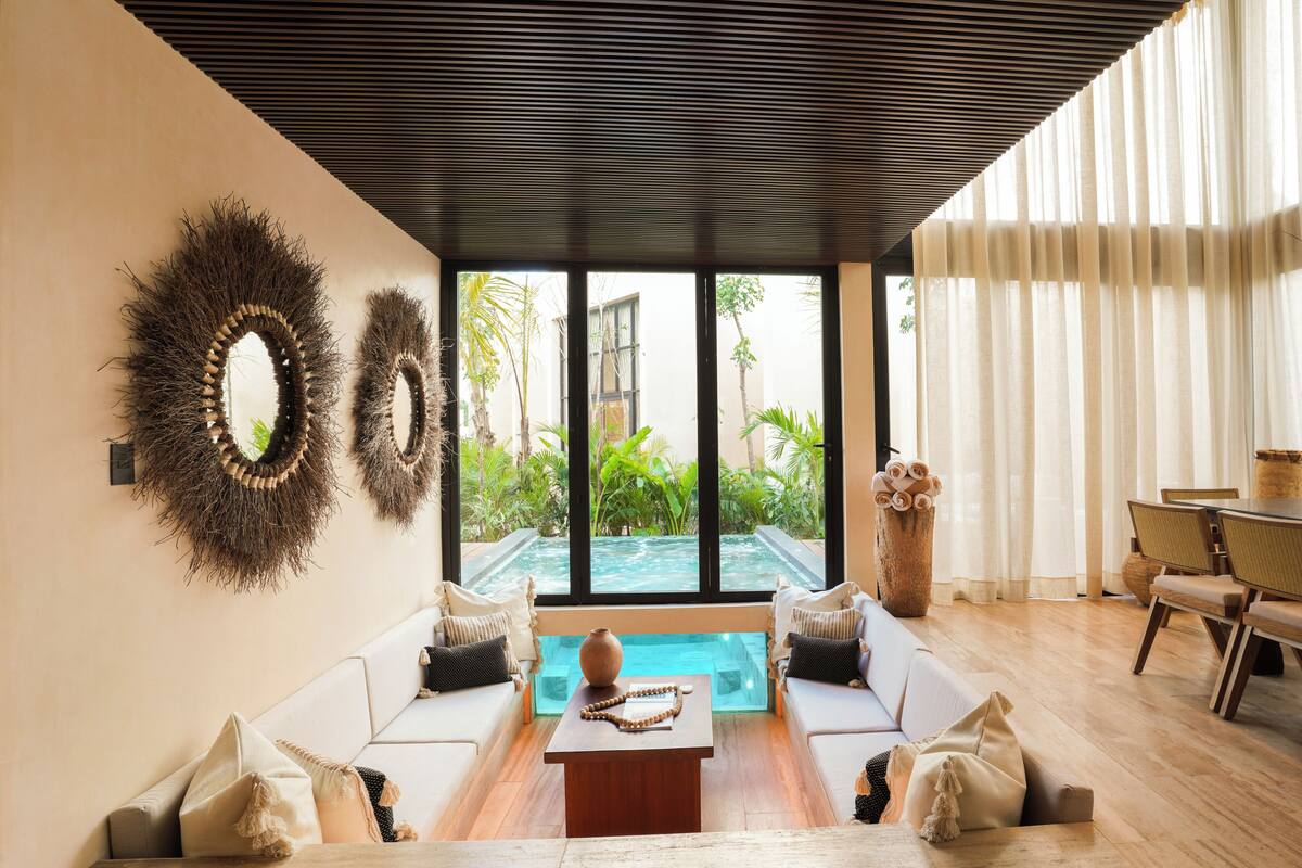 Una sala de estar moderna con piscina, sofás blancos, una mesa de centro de madera y un comedor con sillas.