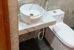 Een badkamer met een wit wastafel, toilet en een marmeren aanrechtblad.