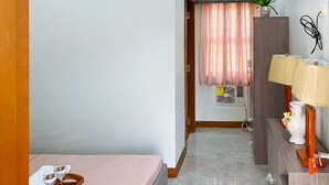 A hotel room with a bed, a desk with a lamp, a potted plant, and a window with curtains. - Leonila S Travellers Inn (Iloilo)