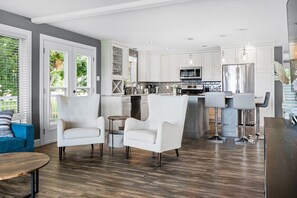 A modern kitchen with white cabinetry, stainless steel appliances, and a bar area with stools.