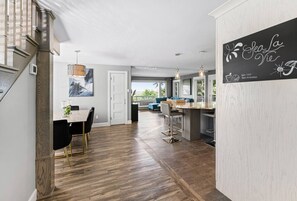 A modern kitchen with a dining area, wooden flooring, and a view to the outside.