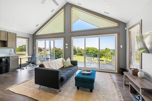 A modern interior with a large dining area, a sofa, and a view of the outdoors.