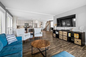 Un salon moderne avec un canapé bleu, une table basse en bois et un téléviseur fixé au mur.