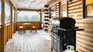 Una cabaña de madera con una parrilla y mesas de picnic.