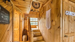 A wooden interior with a staircase, a welcome sign, and a door labeled "GAMES".