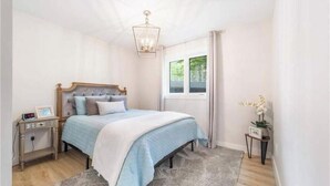A bedroom with a bed, bedside table, nightstand, and a window with curtains. - Richibucto River Getaway (Bass River)