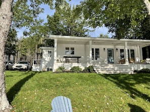 Une maison de plain-pied avec un porche à l’avant, un petit garage attenant et une pelouse bien entretenue.