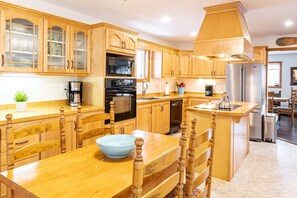 A kitchen with wooden cabinets, a central island, and modern appliances. - Get-A-Way Beach Chalet (Grande-Digue)