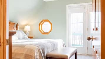 A bedroom with a bed, a bench, a ceiling fan, and a door leading outside.