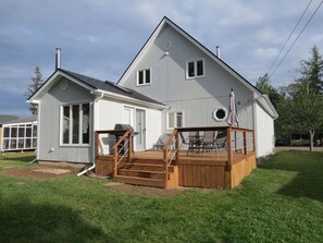 A two-story house with a wooden deck and a small attached garage. - Get-A-Way Beach Chalet (Grande-Digue)