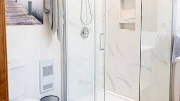 Une salle de bain moderne avec une douche à parois de verre, des toilettes et un porte-serviettes.