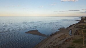 A coastal landscape with a beach, ocean, and a distant shoreline with buildings.