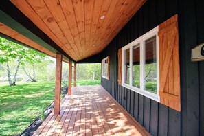 Eine überdachte Holzterrasse mit Blick auf eine grüne Landschaft.