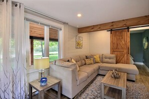 Una sala de estar con un sofá seccional color beige, una mesa de centro de madera y una lámpara.