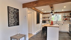 Una cocina moderna con una isla central, vigas de madera y un mural inspirador.