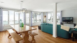 A modern living room with a wooden table, teal sofa, and a television. - East Coastal- Waterfront Cottage (Beaubassin-est)
