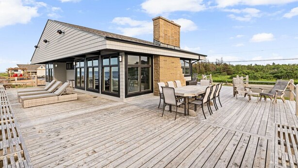 Une maison moderne dotée d’une terrasse, de grandes fenêtres et d’une cheminée en briques.