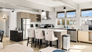 Une cuisine moderne dotée d’un îlot central, de tabourets de bar et d’un coin repas comprenant un canapé et une table basse.