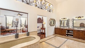 A spacious bathroom with a large mirror, a bathtub, and a vanity with a sink and multiple drawers.