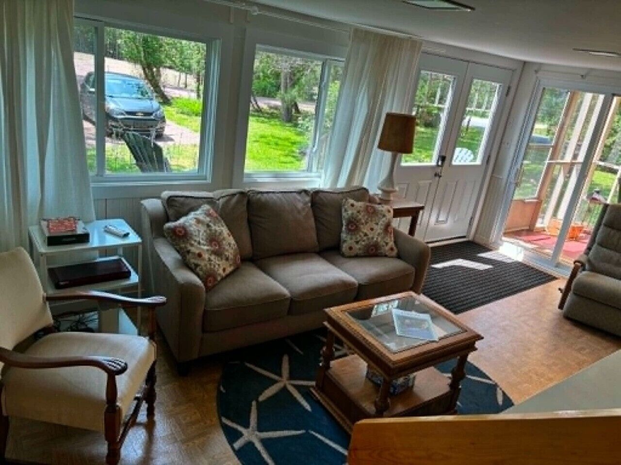 A living room with a sofa, armchairs, a coffee table, and a window with a view of the outdoors.