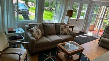A living room with a sofa, armchairs, a coffee table, and a window with a view of the outdoors.