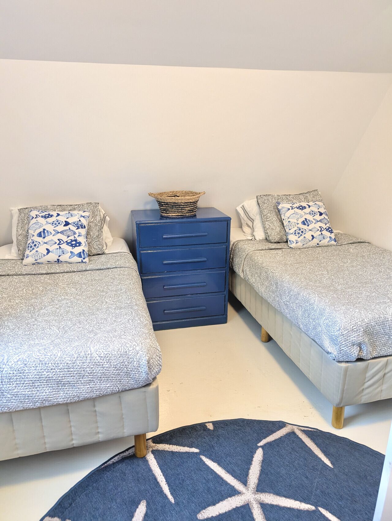 Une chambre avec deux lits, une commode et un tapis.