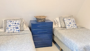 Een slaapkamer met twee bedden, een kapstok en een vloerkleed.