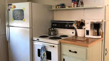 Eine kleine Küche mit Kühlschrank, Herd, Mikrowelle und einer Holzarbeitsplatte.