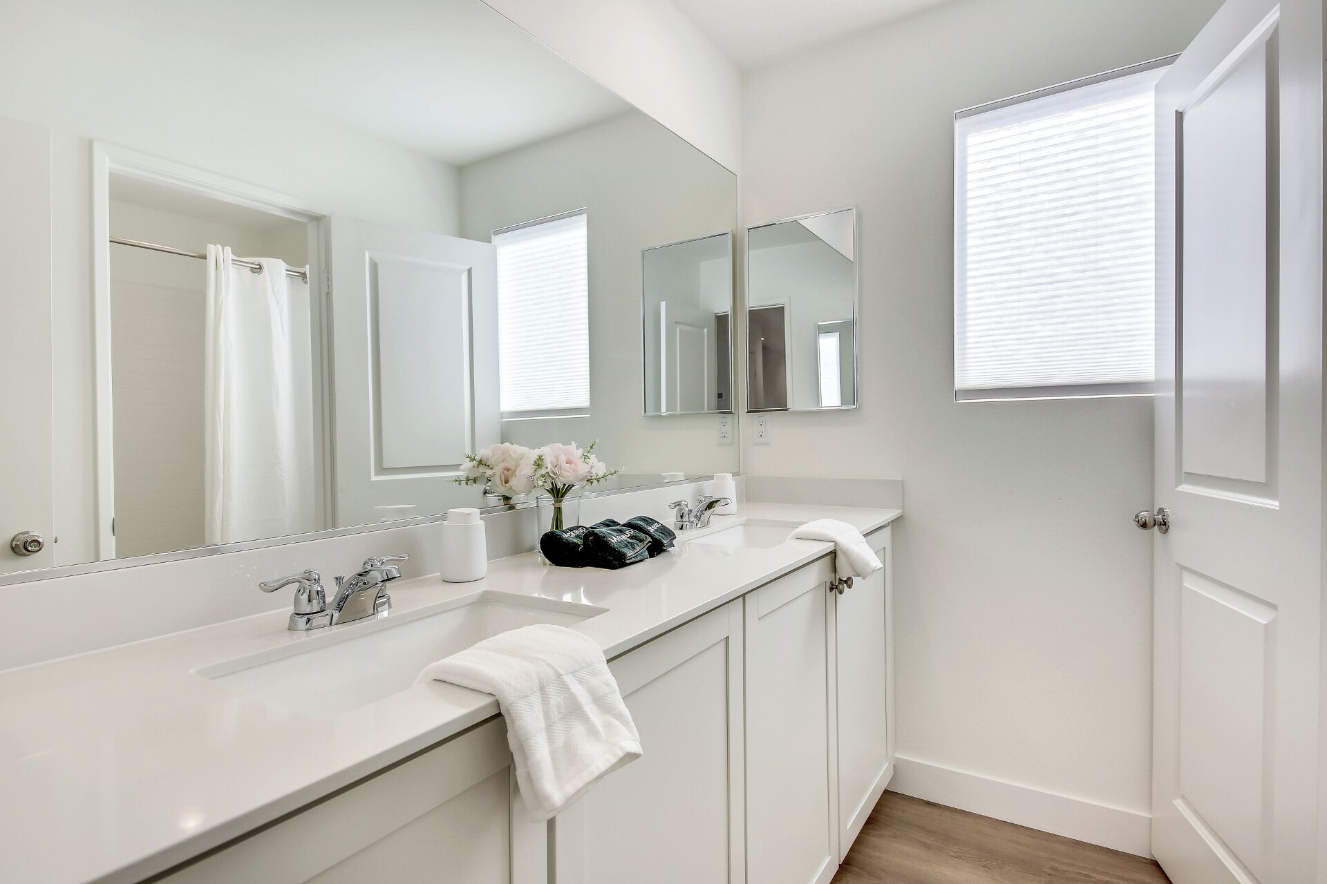 Une salle de bain moderne avec un double vasque, de grands miroirs et un porte-serviettes.