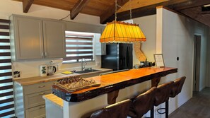 A modern kitchen with a central island, stainless steel appliances, and a hanging pendant light. - Our cozy cabin offers the perfect vacation getaway for the whole family. (Big Bear)