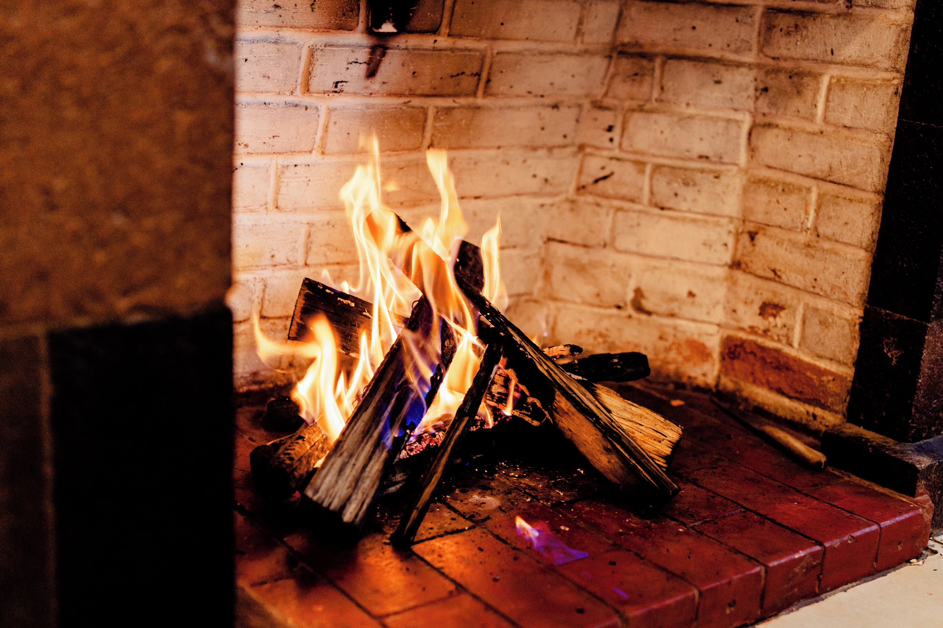 Ein Kamin mit brennenden Holzscheiten und Flammen.