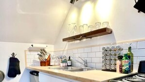 A compact kitchen with white cabinets, a wooden countertop, a built-in oven, and a hanging light fixture. - Finn's Studio Suite Apartment, Alma, Fundy Park (Alma)
