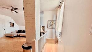 A staircase leading to a second floor with a white railing, a trash can, a ceiling fan, and a framed artwork on the wall. - Finn's Studio Suite Apartment, Alma, Fundy Park (Alma)