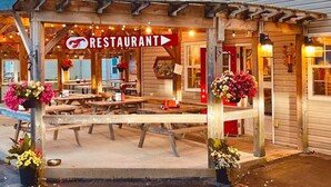 A wooden structure with a sign reading "Alma Lobster Shop" and a "RESTAURANT" sign above a covered outdoor seating area. - Finn's Studio Suite Apartment, Alma, Fundy Park (Alma)