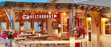 A wooden structure with a sign reading "Alma Lobster Shop" and a "RESTAURANT" sign above a covered outdoor seating area.