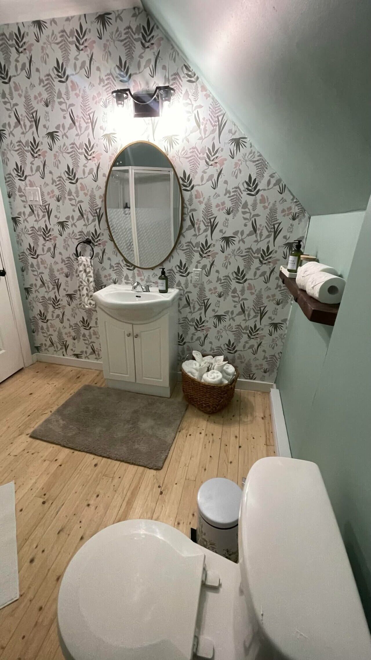 Een badkamer met een wastafel, spiegel, toilet en een klein vloerkleed.